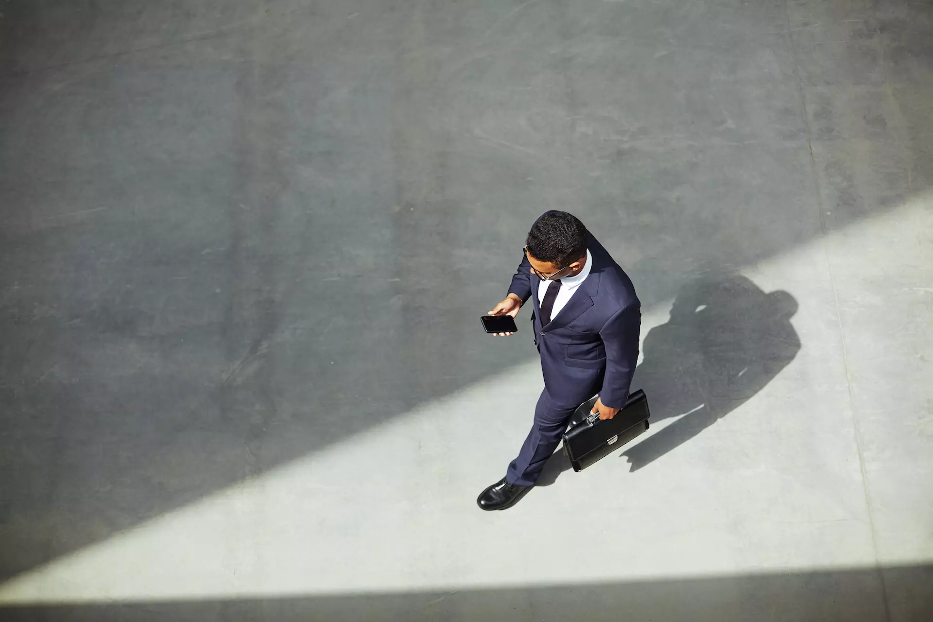 Hombre de negocios elegante con maletín con teléfono móvil en movimiento