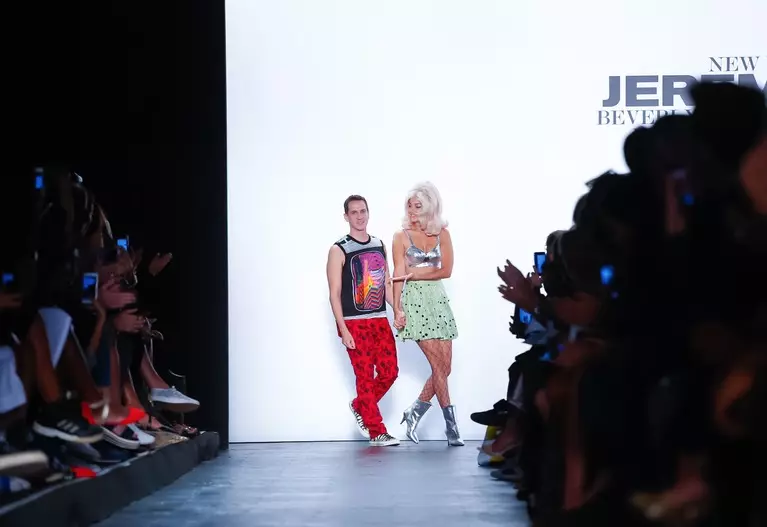 Jeremy Scott, ɗan wasan yara na zamani na zamani na zamani na zamani, ya kammala karatun digiri don yin sarauta. Ya sake farfado da Moschino, sanye da gimbiya pop Miley Cyrus don watsa shirye-shiryen watsa labarai na MTV VMAs kuma ya kasance batun batun shirin gaskiya, "Jeremy Scott: The People's Designer," firamare a New York Satumba 15. Ya sanya masu shakka dariya da murmushi da murmushi kuma yi nishadi da wayonsa; yanzu suna tsammanin hakan. Shin al'amuran sun zama albatross?