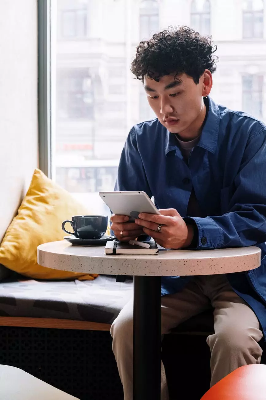 hombre con camisa de vestir azul sentado en una silla mientras lee un libro. Foto de cottonbro en Pexels.com