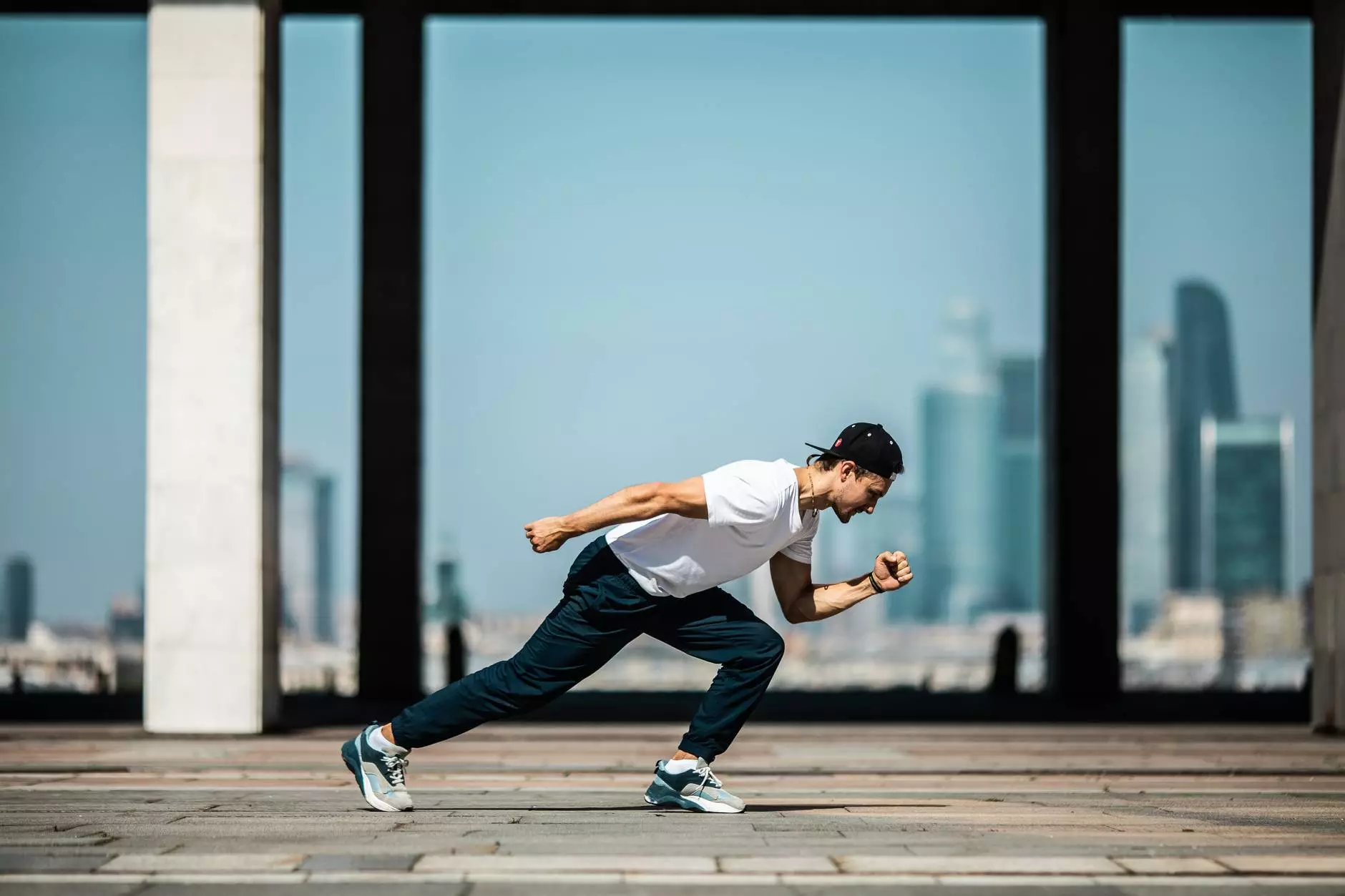 Hombre con camiseta blanca y pantalón negro en posición de correr