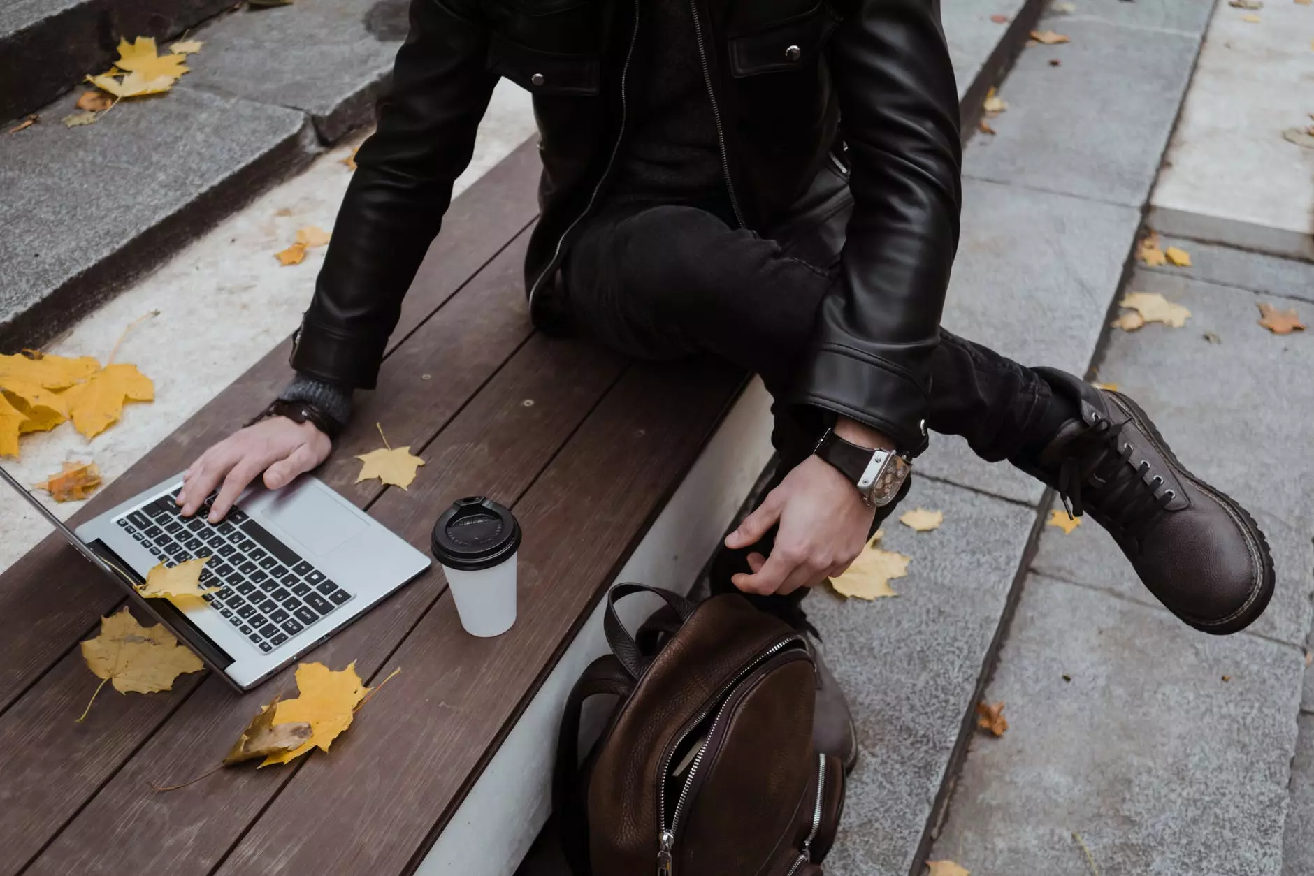 taong nakasuot ng itim na leather jacket na gumagamit ng laptop